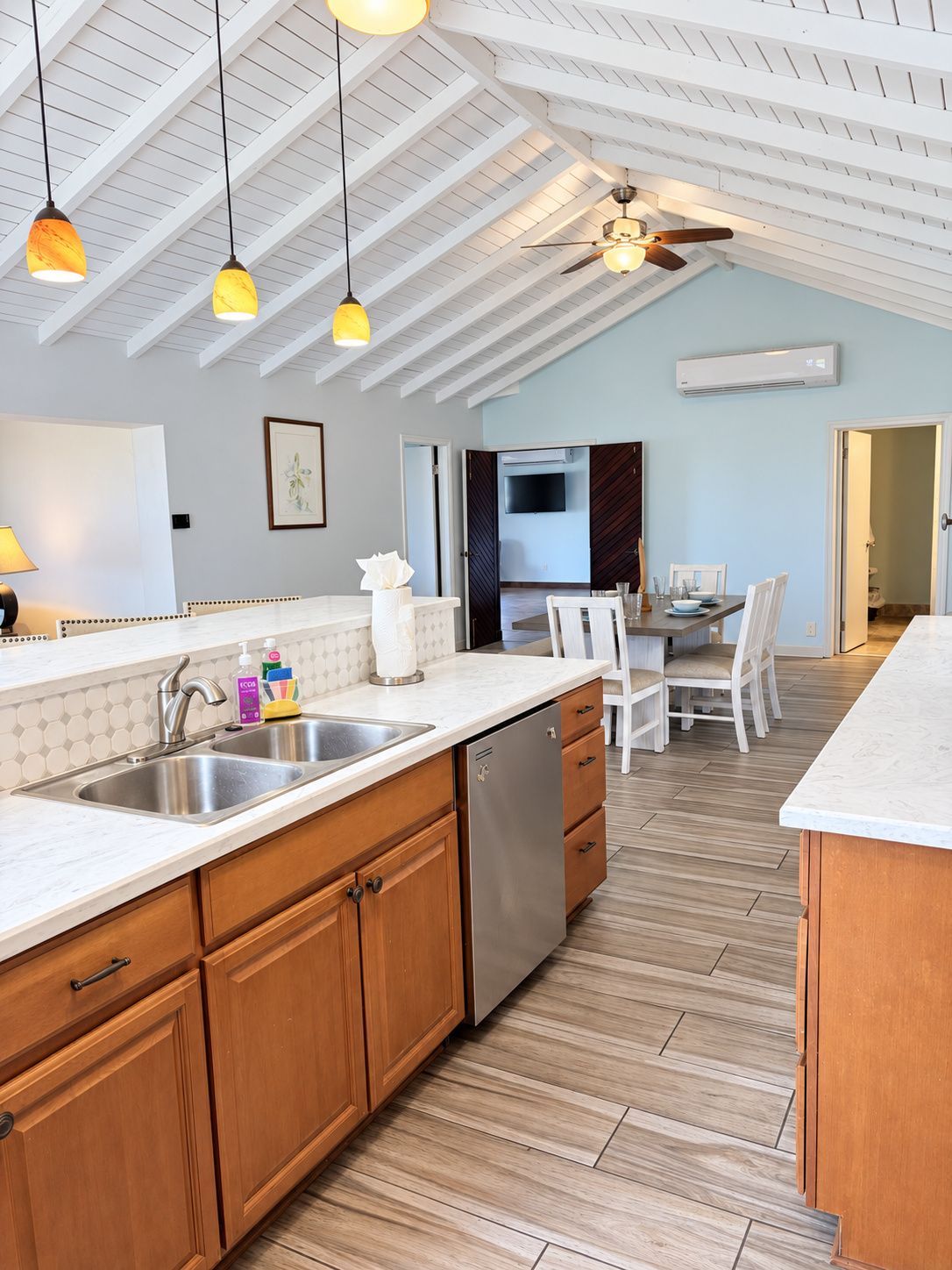A modern kitchen with a central island, wooden cabinets, and a built-in dishwasher.