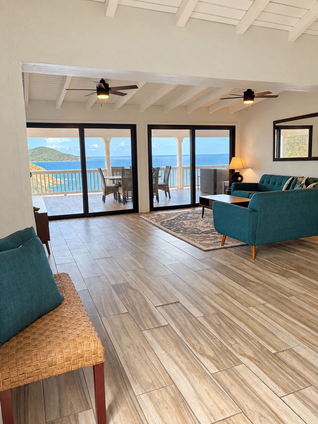 A spacious living area with a view of the sea, a ceiling fan, and a sofa.