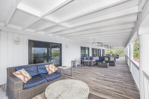 A covered outdoor area with a wicker sofa, a round table, and a seating area with cushions. - Isla Paradiso, A Private Oasis (St Thomas)
