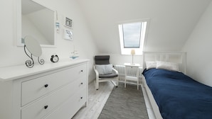 Een slaapkamer met een bed, een kaptafel, een spiegel en een raam.