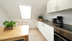 Een moderne keuken met witte kastjes, een houten eettafel en een raam dat natuurlijk licht binnenlaat.