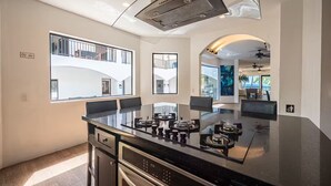 Una cocina moderna con una isla grande, electrodomésticos integrados y amplios ventanales con vistas al exterior del edificio.