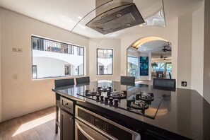 A modern kitchen with a large island, built-in appliances, and large windows offering views of the building's exterior. - BEACH FRONT VILLA 11 Bedrooms Casa Playa Del Rey House (Jaco)