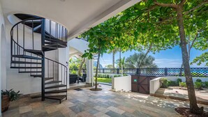 Un interior moderno con una escalera de caracol, zona de estar al aire libre y vistas al mar.