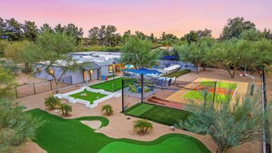 A golf course with a putting green, sand bunkers, and a small building with a patio. - Fun-Filled Oasis • Pool, Pickleball, Games Galore (Scottsdale)