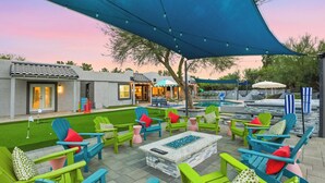 An outdoor seating area with colorful Adirondack chairs and a fire pit, under a large shade structure. - Fun-Filled Oasis • Pool, Pickleball, Games Galore (Scottsdale)