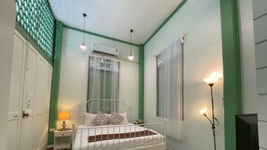 A bedroom with a bed, bedside table, lamp, air conditioning unit, and a television on a stand. - greenteakhouse (Bangkok)