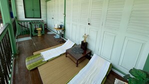 A room with a green and white color scheme, a wooden floor, a green door, and a white wall with multiple doors. - greenteakhouse (Bangkok)