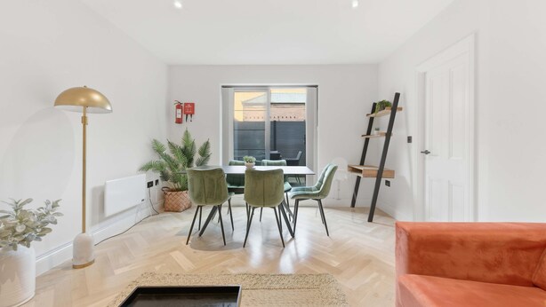 Ein modernes Wohnzimmer mit Essbereich, einer Couch, einer Lampe und Blick ins Freie.