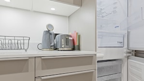 Eine moderne Küche mit weißen Schränken, einem Wasserkocher, einem Toaster und einem Kühlschrank mit Wasserspender.