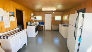A compact kitchen with a stove, microwave, refrigerator, and wooden cabinets.