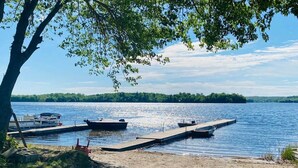 A lakeside dock with boats, a clear sky, and a forested shoreline.