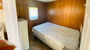 Una habitación pequeña con una cama individual, una ventana con cortina y un armario blanco.