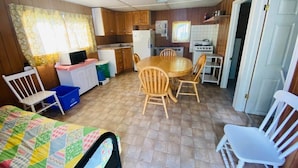 Una cocina compacta con comedor, un refrigerador pequeño, estufa y televisor.