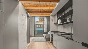 Eine moderne Küche mit grauen Schränken, einer Holzbalkendecke und Blick ins Freie.
