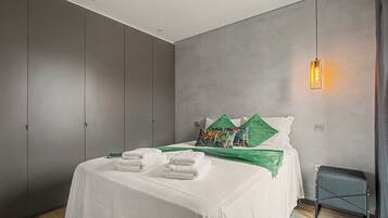 Un dormitorio moderno con cama, almohadas, una mesita de noche y una lámpara colgante.