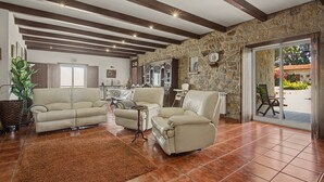 Un salon spacieux avec un mur en pierre, une cheminée et un coin repas comprenant une table et des chaises.