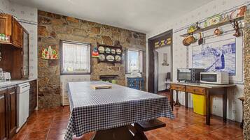 Una cocina con pared de piedra, una mesa a cuadros y suelo de baldosas.