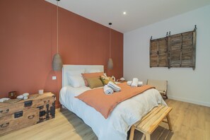 Un dormitorio con cama, mesita de noche, banco de madera y cómoda.