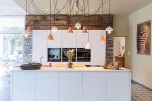 A modern kitchen with pendant lighting, a central island, and a stone accent wall.