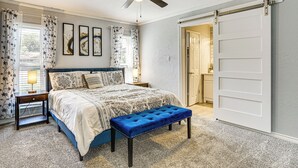 Un dormitorio con cama, un banco, un ventilador de techo y una puerta.