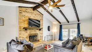 Una sala de estar con chimenea de ladrillo, vigas de madera y un televisor montado en la pared. Hay dos sofás y una mesa de centro.