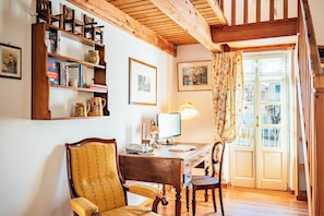Une pièce chaleureuse avec un bureau en bois, une chaise, une bibliothèque et une fenêtre avec des rideaux.