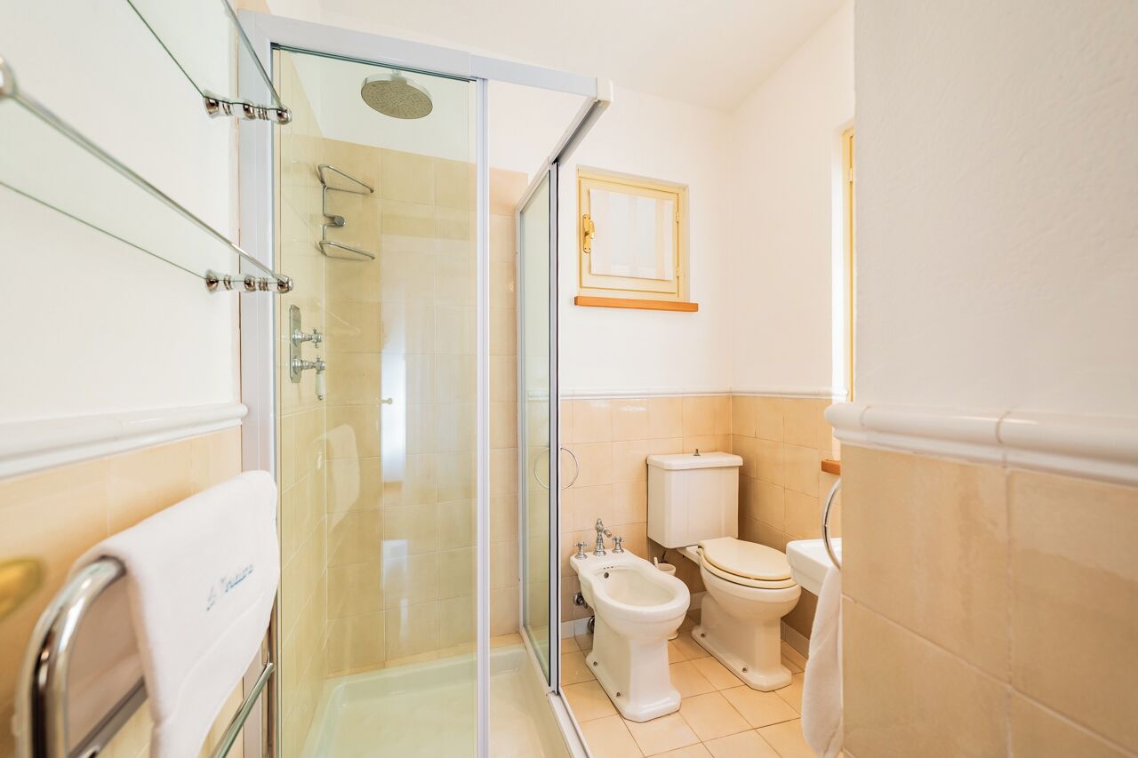 Un baño moderno con cabina de ducha de vidrio, un bidé y un inodoro.