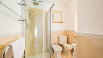 Un baño moderno con cabina de ducha de vidrio, un bidé y un inodoro.