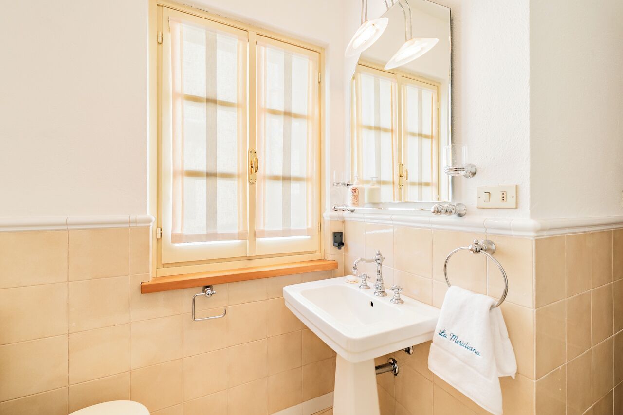 Une salle de bain avec une fenêtre, un lavabo et un porte-serviettes.