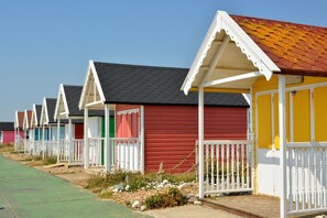 Une rangée de cabanes de plage avec des rampes blanches et un chemin verdoyant.