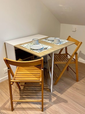 Una mesa de comedor con dos sillas, un armario blanco y un mantel individual estampado.
