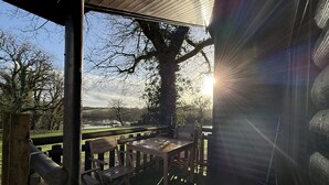 Un espace extérieur aménagé avec du mobilier en bois, offrant une vue sur un lac et des arbres.