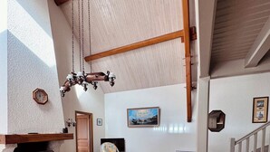 A spacious dining area with a long wooden table and chairs, a stone fireplace, and a hanging light fixture. - The Saint Colomban house (Carnac)