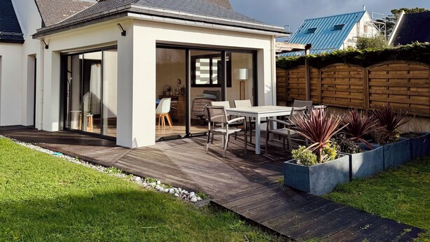A modern house with a patio, a covered outdoor seating area, and a well-maintained garden. - The Saint Colomban house (Carnac)