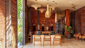 Ein modernes Interieur mit einer Holzwand, einem Essbereich mit Rattan-Stühlen und einem Deckenventilator.