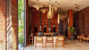 A modern interior with a wooden wall, a dining area with rattan chairs, and a ceiling fan. - Bloom Tulum | 4-BR Apartment | w/ Fully Equipped Kitchen + Pool (Tulum)