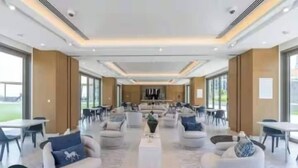 A spacious hotel lobby with multiple seating areas, a central coffee table, and large windows offering views of the outdoors. - Vogue | Downtown with Direct Access to Dubai Mall (Dubai)