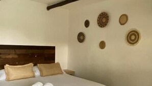 A bedroom with a wooden headboard, a bed with white linens, and decorative wall art. - Hot Chipilin El Paredon (Sipacate)