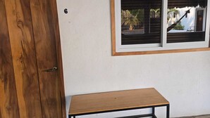 A wooden door, a small table, and a window with a view of palm trees and a house. - Hot Chipilin El Paredon (Sipacate)