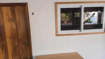 A wooden door, a small table, and a window with a view of palm trees and a house.