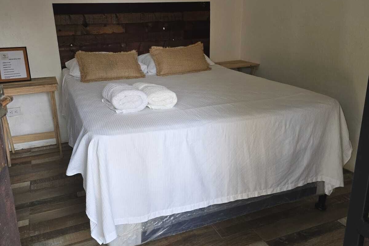 Una cama con sábanas blancas, dos almohadas marrones y un cabecero de madera oscura.