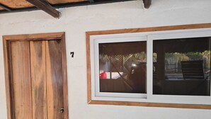 A wooden door with a number 7, a window with a view of a garden, and a white wall. - Hot Chipilin El Paredon (Sipacate)
