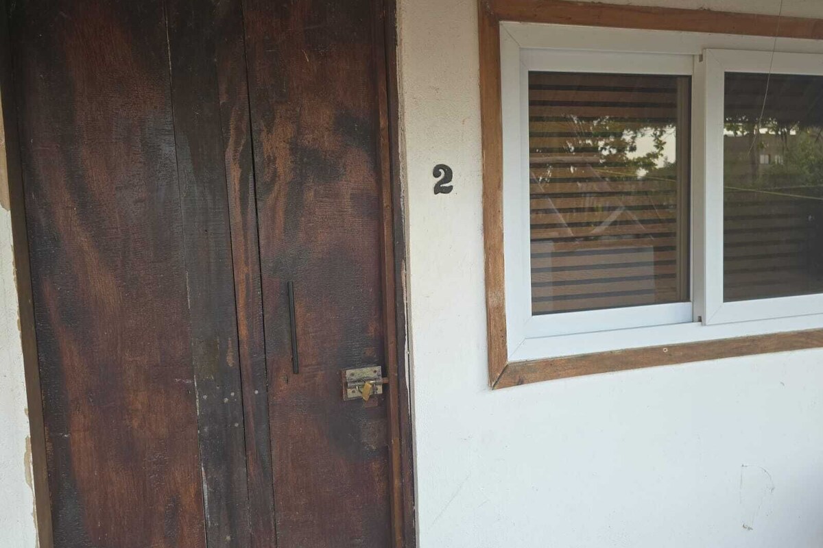 Una puerta de madera con un picaporte de latón y una ventana con persianas.