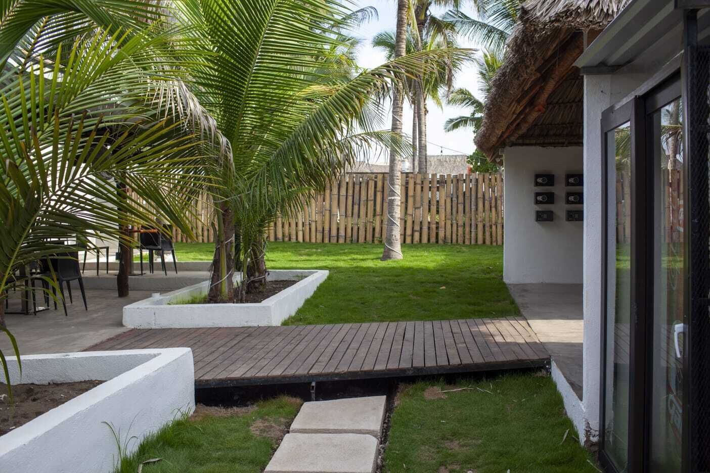 A patio area with a wooden deck, palm trees, and a bamboo fence.