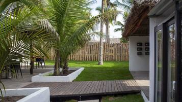 A patio area with a wooden deck, palm trees, and a bamboo fence.