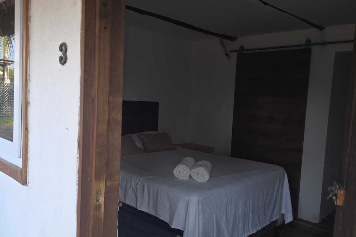 Un dormitorio con una cama, piso de madera y una puerta que da a otra habitación.