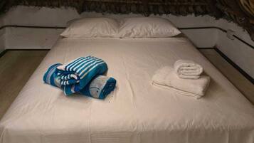 A room with a thatched roof, a bed with white linens, and a blue striped blanket.