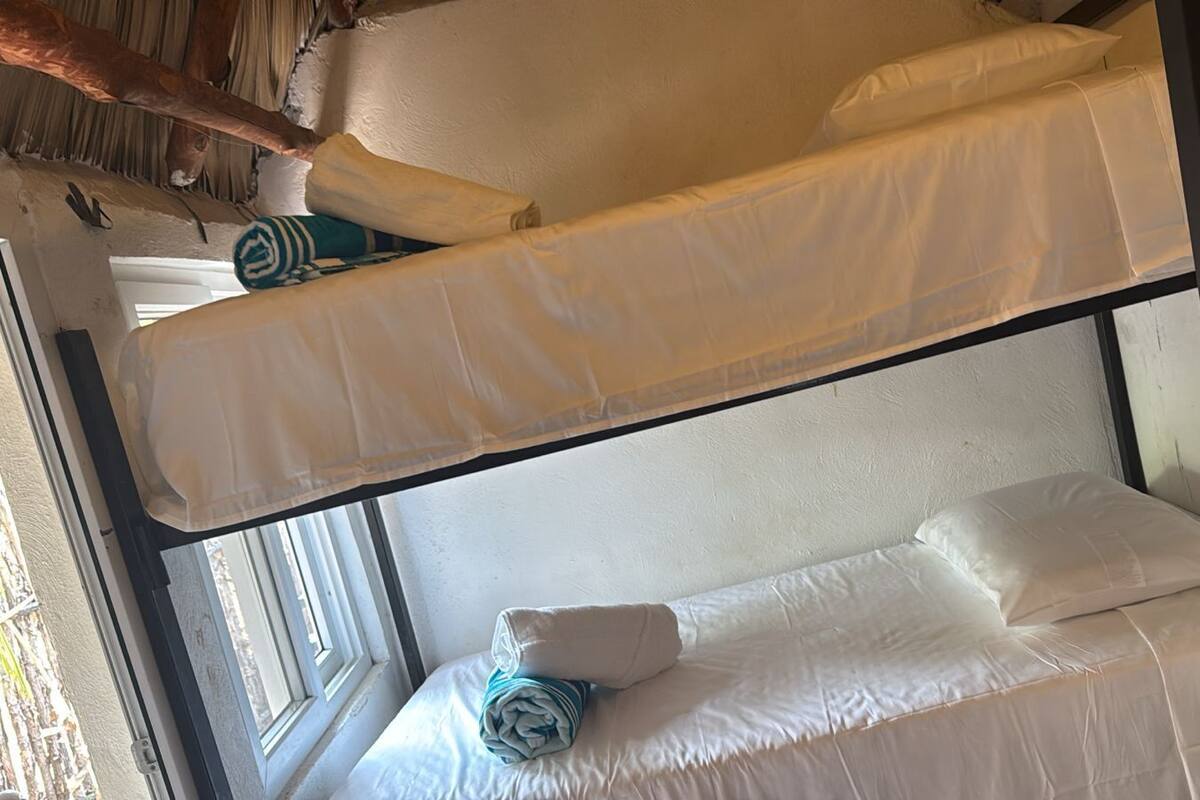 Una cama litera con ropa blanca, una ventana con vistas y una toalla en la litera inferior.