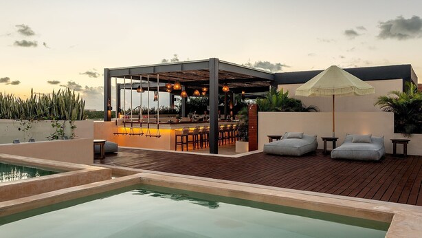 A rooftop bar with outdoor seating and a pool.